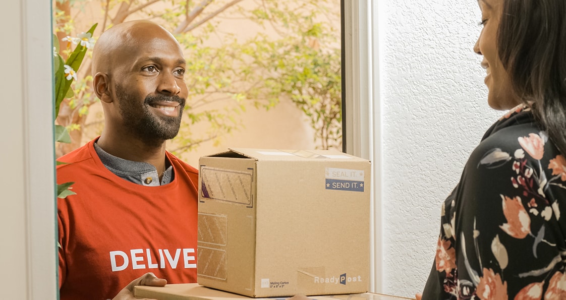 smiling deliveryman giving two parcels to a person at his home