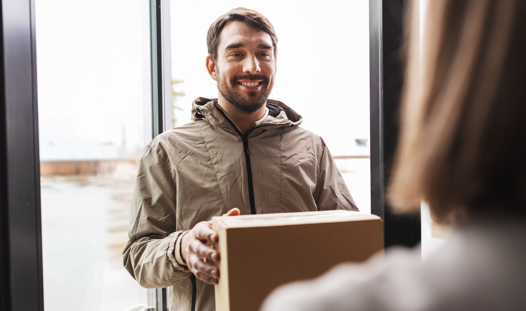 Livreur donnant un colis à une femme à son domicile.