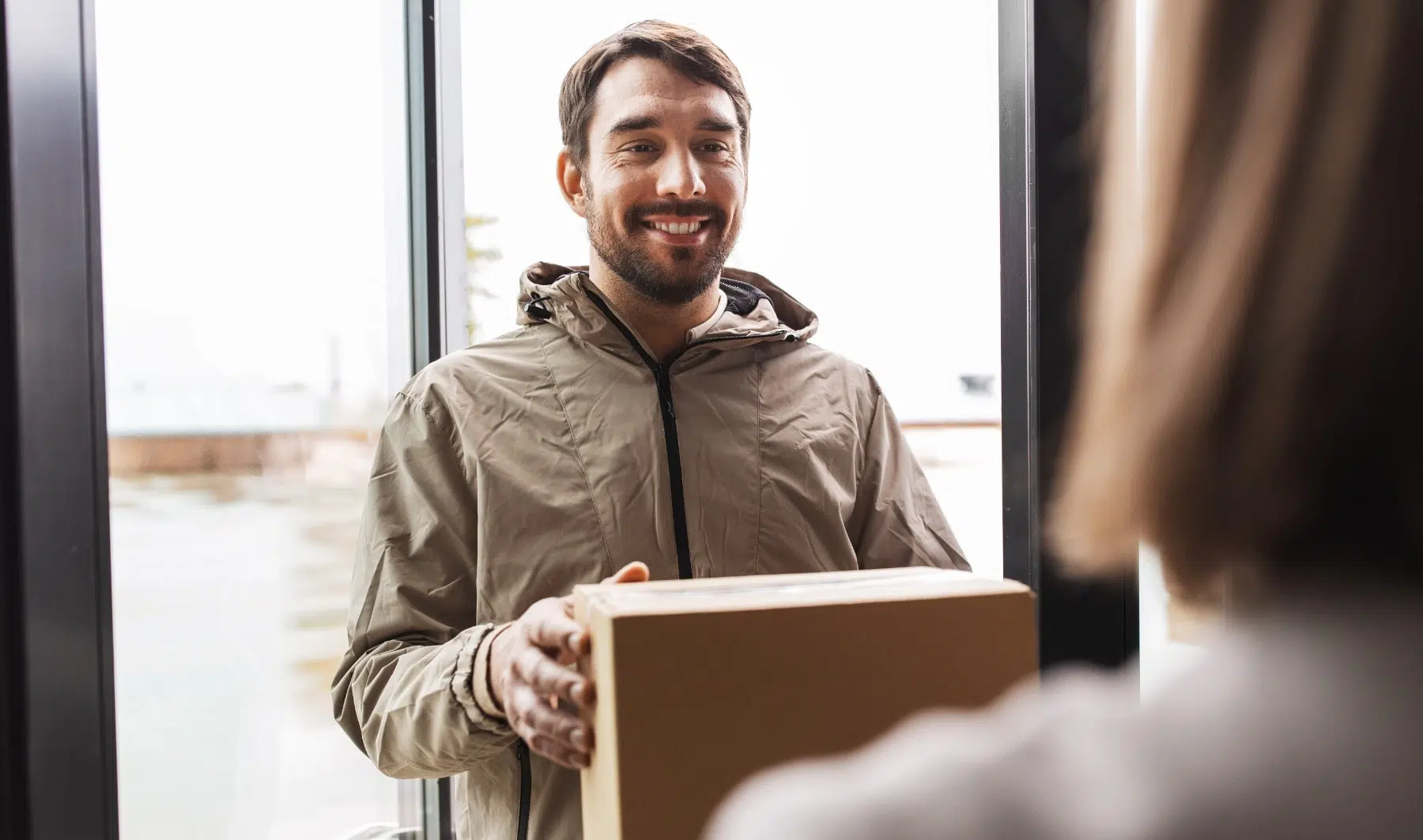 Livreur souriant remettant un colis à un client pendant une livraison à domicile