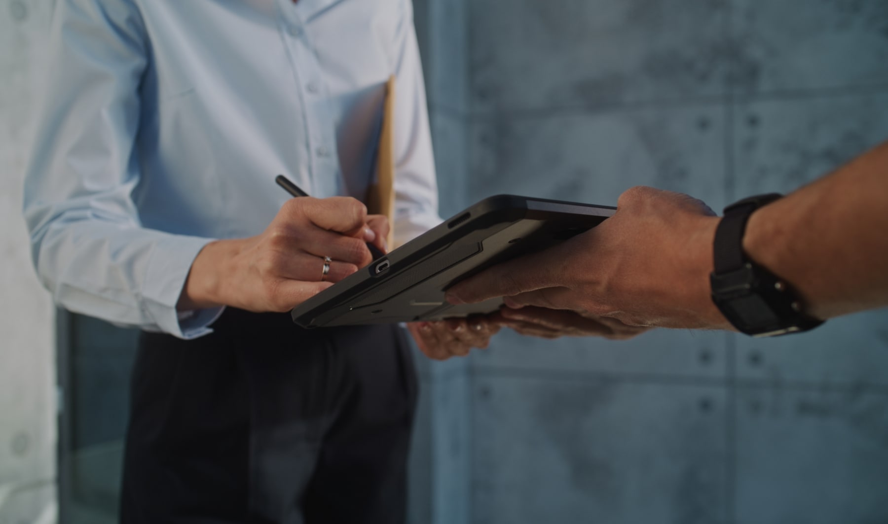Femme tenant un colis signant la réception de ce colis sur une tablette.