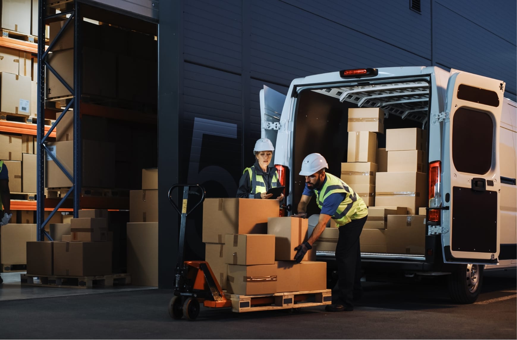 Two logistics operators load packages onto a truck.