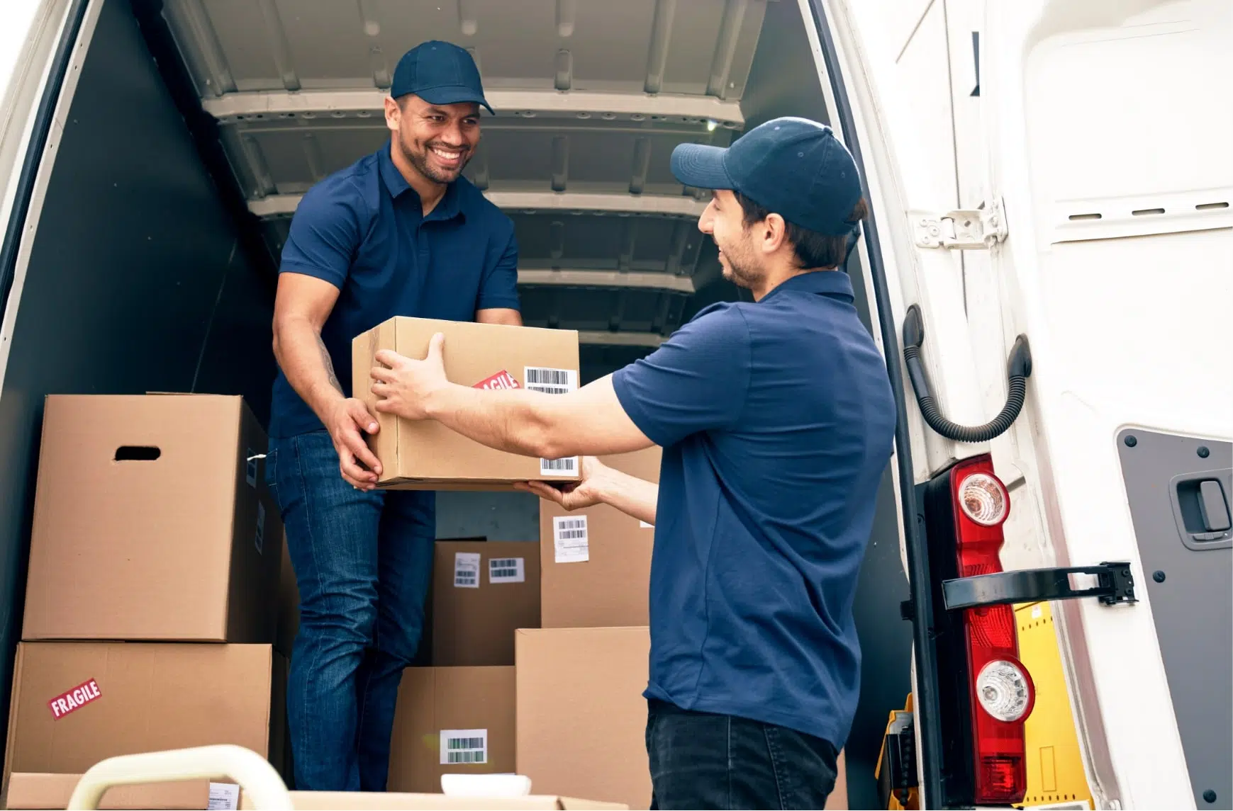 A delivery driver unloads parcels from his vehicle and hands them over to a customer.