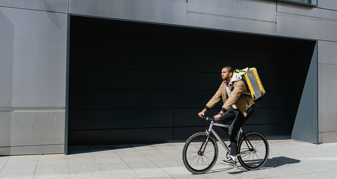 eine Person auf einem Fahrrad, die eine Tasche mit Paketen trägt