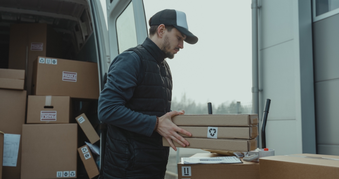 Repartidor que carga sus paquetes en su camión antes de empezar su ruta de entrega