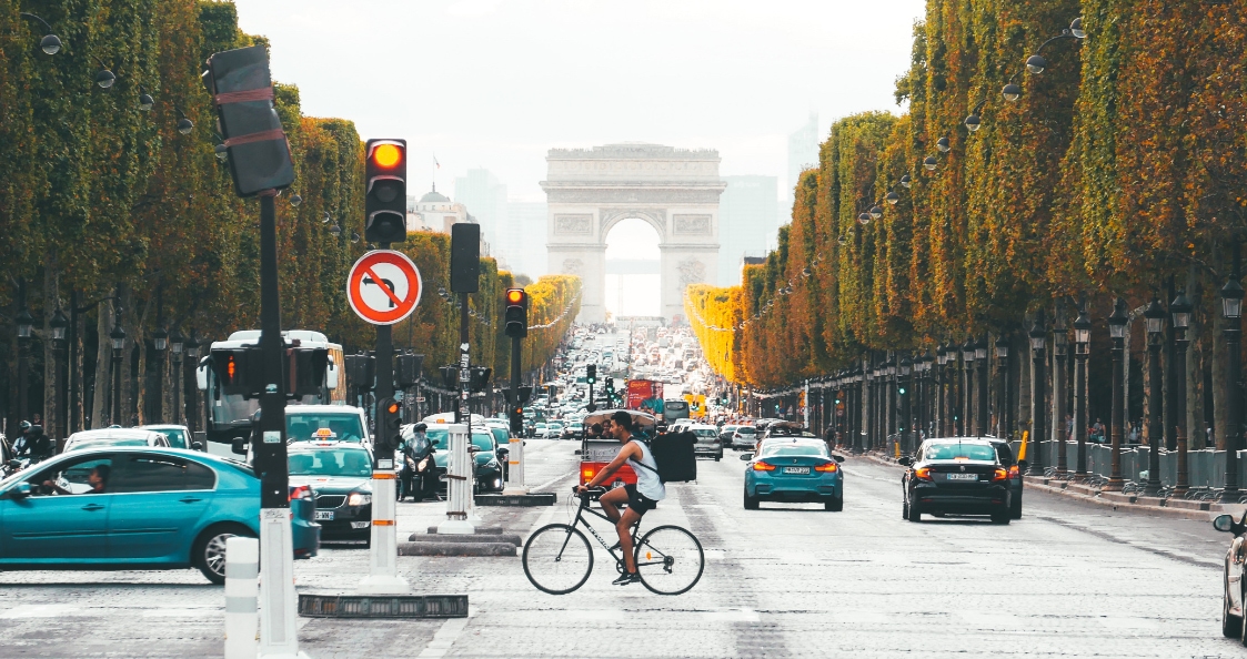 un livreur à vélo qui circule sur les Champs Élysées à Paris