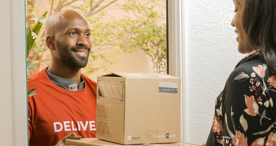 un repartidor sonriente que entrega dos paquetes a una persona