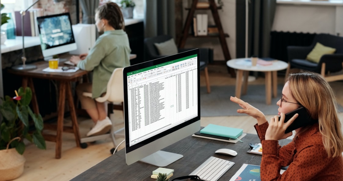 eine Person arbeitet am Telefon an einer Excel-Datei