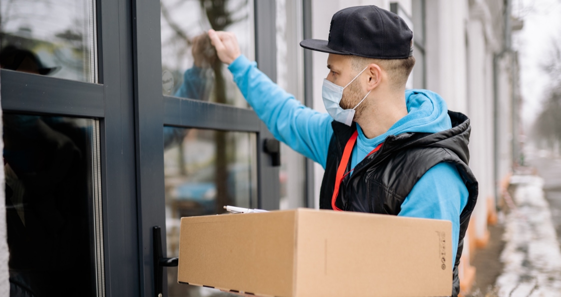 un hombre con gorra que toca a la puerta para entregar un paquete a un cliente