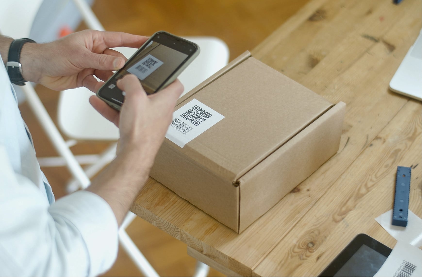 A person scans a QR code on a parcel with a mobile phone. 