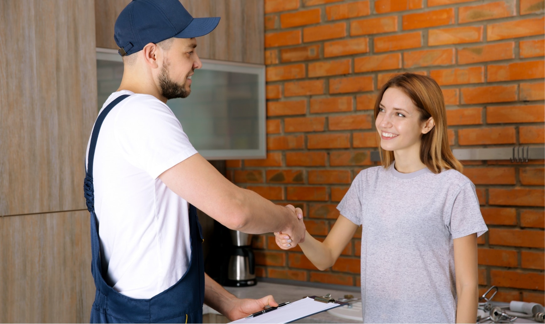 A technician shakes hands with a woman in her home.