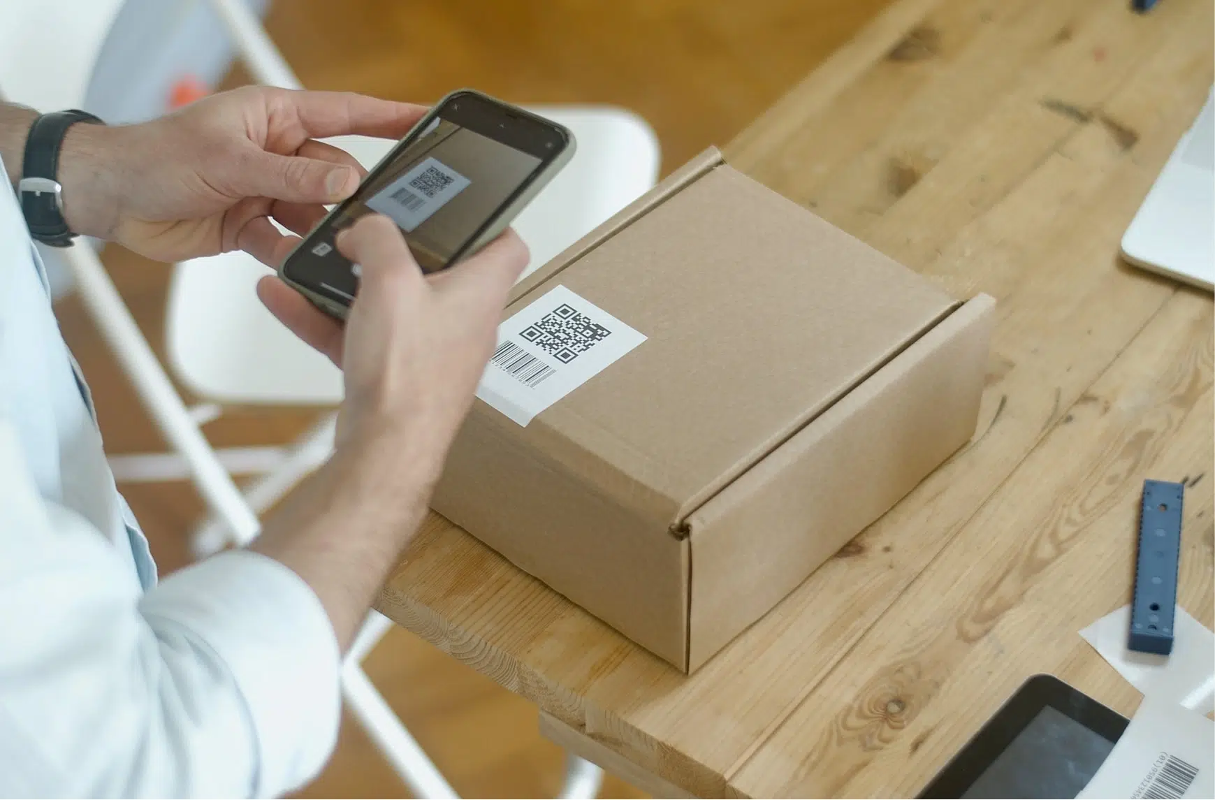 Eine Person scannt einen QR-Code auf einem Paket mit einem Mobiltelefon.