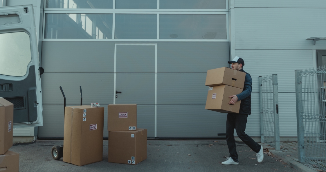 delivery person loading parcels into a vehicle at a warehouse