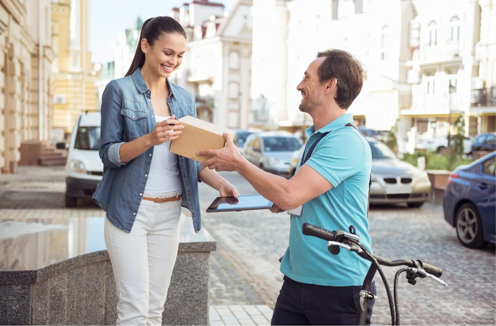 Un livreur à vélo donne un colis à une cliente.